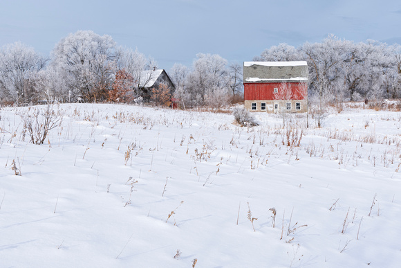snowy field and barns of rural prairie landscape
