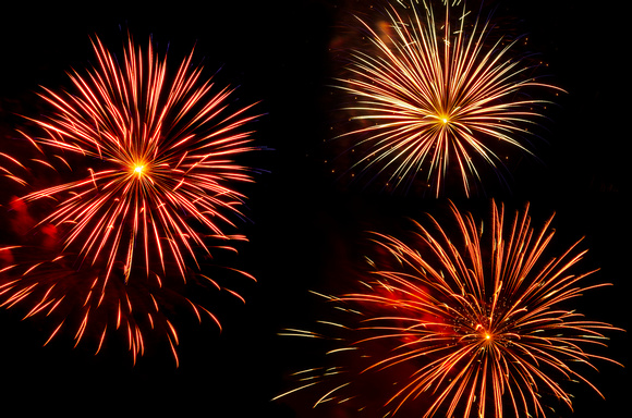 Colorful bursts of fireworks trio against black sky